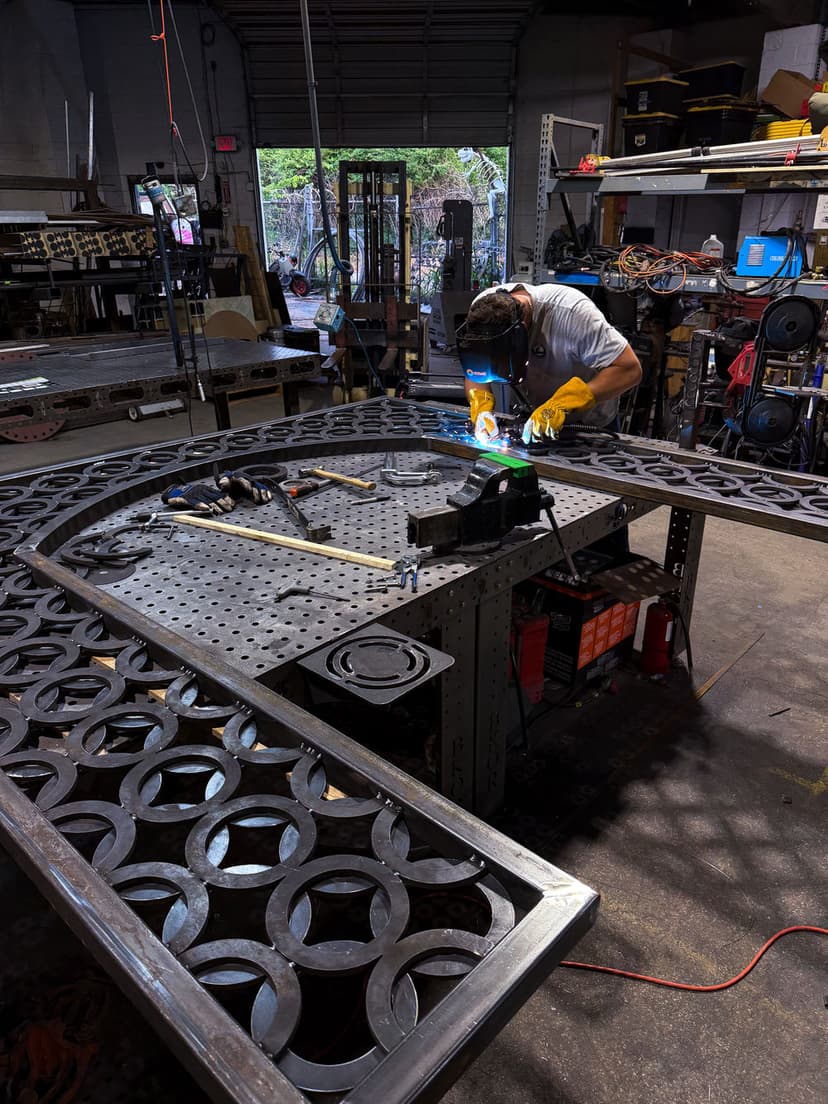 Welder in workshop fabricating decorative metalwork with welding tools and equipment.